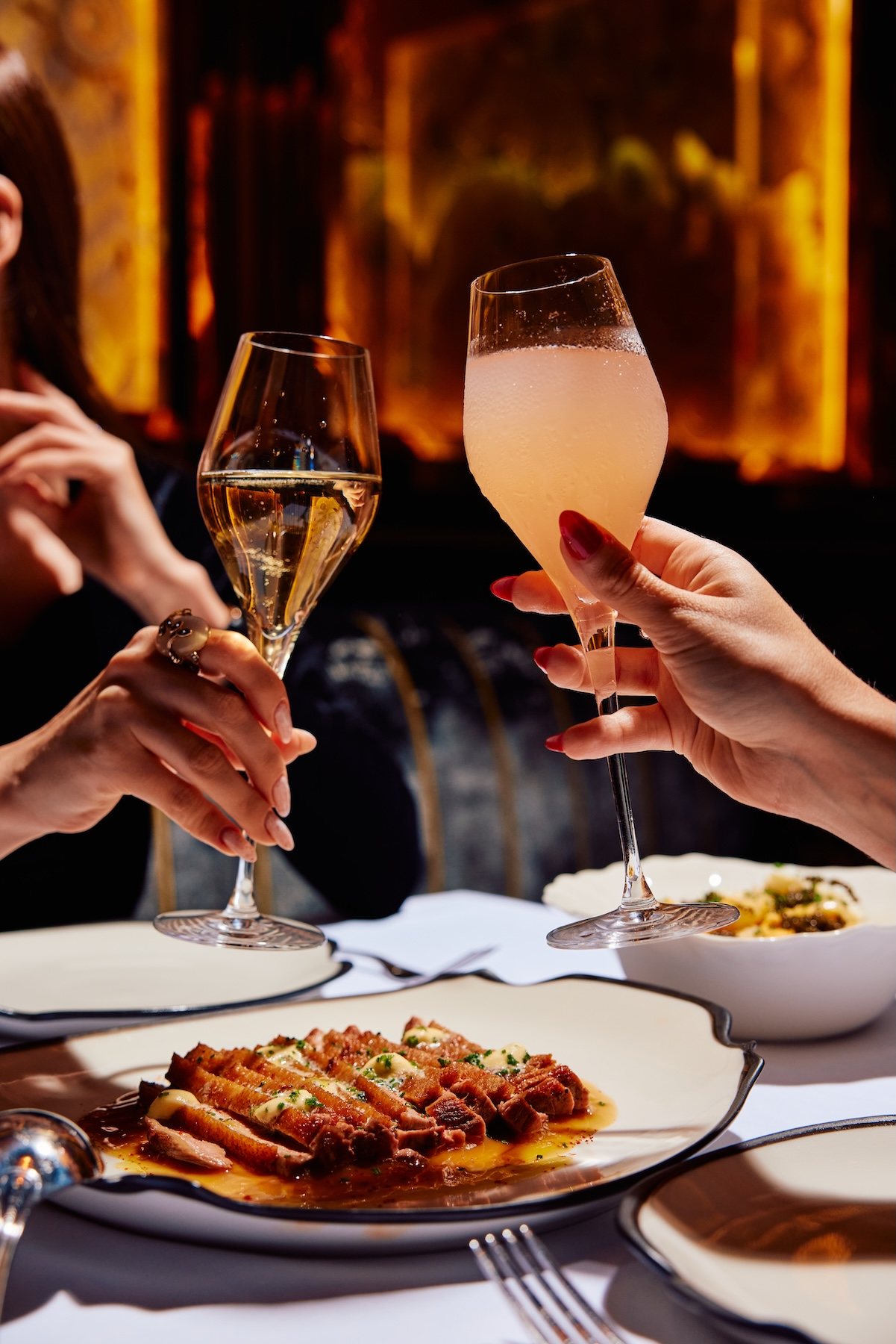 A toast with champagne and a cocktail over dinner at Adaline Dubai
